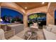 Night view of a cozy outdoor patio with comfortable seating area and backyard views under a vaulted, stone-covered ceiling at 9801 Orient Express Ct, Las Vegas, NV 89145