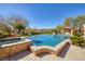 A backyard paradise featuring a large pool, hot tub, covered seating area and landscaped surroundings under a blue sky at 9801 Orient Express Ct, Las Vegas, NV 89145