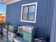 An exterior view of the side of the home showing blue wood siding, a window, and some boxes at 11 Magnesium St, Henderson, NV 89015