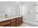 Modern bathroom featuring double sinks with wooden cabinets, a glass-enclosed shower, and bright, neutral finishes at 11321 Golden Chestnut Pl, Las Vegas, NV 89135