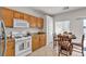 Open kitchen with white appliances, wooden cabinets, granite countertops, and an adjacent dining area at 2572 Favorable Pointe Ct, Henderson, NV 89052