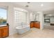 Light-filled bathroom with soaking tub, cabinets, and tile floors at 2694 Caumsett Ct, Las Vegas, NV 89117