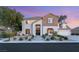 Charming two-story home with stone accents, lush landscaping, and a welcoming entrance at dusk at 2694 Caumsett Ct, Las Vegas, NV 89117