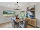 Dining room with wood table, grey chairs, modern chandelier, art, and views of the golf course at 2817 Billy Casper Dr, Las Vegas, NV 89134