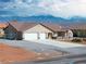 Exterior of a home with a three-car garage and desert landscaping against a mountain backdrop at 340 Domingo St, Pahrump, NV 89048