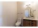 Well-lit half bathroom features a wood cabinet vanity with an oval mirror and modern fixtures, plus a toilet at 380 Claremont St, Boulder City, NV 89005