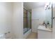 Bright bathroom featuring a shower-tub combination with a sliding glass door and a vanity with updated lighting at 380 Claremont St, Boulder City, NV 89005