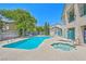Community pool area featuring a sparkling pool, hot tub, lounge chairs, and mature trees at 5161 Lindell Rd # 104, Las Vegas, NV 89118