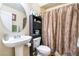 Cozy half bathroom featuring a pedestal sink, a leaf-patterned shower curtain, and tile flooring at 6177 W Cougar Ave, Las Vegas, NV 89139