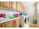 Functional laundry room with overhead cabinets, a utility sink, and modern washer and dryer at 6177 W Cougar Ave, Las Vegas, NV 89139