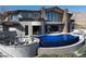 An infinity pool highlights the backyard of a luxurious modern home with mountain views at 64 Promontory Ridge Dr, Las Vegas, NV 89135