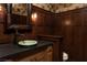 Elegant powder room with dark wood paneling, unique sink, and stylish lighting at 64 Promontory Ridge Dr, Las Vegas, NV 89135