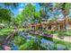 Backyard featuring a serene pond with stone features, lush green grass, and mature trees, creating a peaceful oasis at 7803 Canoe Ln, Las Vegas, NV 89145