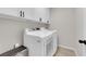 A laundry room with a white front load washer and dryer and updated white cabinets above at 7803 Canoe Ln, Las Vegas, NV 89145