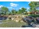 Beautiful water feature with cascading waterfalls, lush landscaping, and mature trees creating a tranquil backyard at 7803 Canoe Ln, Las Vegas, NV 89145