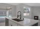 Kitchen island with sink, stainless steel dishwasher, light countertop and black faucet with a view to the backyard and fireplace at 793 Vortex Ave, Henderson, NV 89002