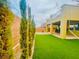 Large backyard offers green turf, tall hedges, outdoor kitchen, and string lights at 806 Neath Ave, Las Vegas, NV 89178