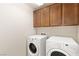 This laundry room has a side-by-side washer and dryer along with above storage in wood cabinets at 806 Neath Ave, Las Vegas, NV 89178