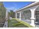 Outdoor covered patio and backyard featuring stucco pillars, artificial grass, and stone walls at 897 Cavaison Ave, Las Vegas, NV 89123