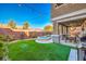 Backyard with artificial grass, in-ground spa, covered patio, and string lights at 10466 Smokewood Rd, Las Vegas, NV 89135