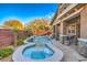 The backyard features a uniquely shaped pool with a spa, a waterfall feature, and a covered patio area for outdoor enjoyment at 10466 Smokewood Rd, Las Vegas, NV 89135