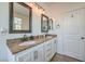 Well-lit bathroom featuring double sinks with granite countertops, stylish mirrors, and white cabinetry, offering a clean aesthetic at 10466 Smokewood Rd, Las Vegas, NV 89135