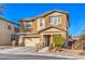 Tan, two-story home with a two-car garage, desert landscaping, and sidewalk at 10466 Smokewood Rd, Las Vegas, NV 89135