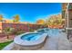 A backyard pool oasis featuring a spa, cascading waterfalls, lush landscaping, and a brick fence for added privacy at 10466 Smokewood Rd, Las Vegas, NV 89135