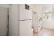 Bright laundry area with stacked washer and dryer, mini fridge, and ample shelving at 11125 Twilight Times Ct, Las Vegas, NV 89135