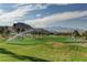 Beautifully manicured golf course with lush green fairways, tall palm trees, and a stunning mountain range in the background at 33 Chateau Whistler Ct, Las Vegas, NV 89148