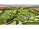 Aerial view of a lush golf course with water features and the city skyline in the distance at 3680 Belvedere Park Ln, Las Vegas, NV 89141