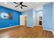 A bright bedroom with a ceiling fan, wood floors, and a view to the next room at 3680 Belvedere Park Ln, Las Vegas, NV 89141