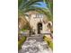Elegant home entrance with a stone pathway, black iron gate, arched doorway, and lush palm trees at 3680 Belvedere Park Ln, Las Vegas, NV 89141