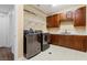 Laundry room with a stainless-steel washer and dryer, as well as wooden cabinets and a sink at 3680 Belvedere Park Ln, Las Vegas, NV 89141