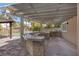 An outdoor kitchen features a built-in grill, sink, and bar area under a pergola, perfect for entertaining at 3680 Belvedere Park Ln, Las Vegas, NV 89141