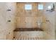 Luxurious shower with travertine tile, bench, and glass door at 3680 Belvedere Park Ln, Las Vegas, NV 89141