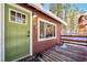 Close-up of the charming front entrance with a vibrant green door and rustic wooden deck at 4165 Mont Blanc Way, Mount Charleston, NV 89124