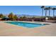 Large community pool with a clear blue water, surrounded by palm trees, seating, and mountain views at 4459 S Glory Vine Ln, Pahrump, NV 89061