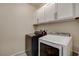 Clean laundry room featuring gray and white, front-load washer and dryer with white cabinets above at 4459 S Glory Vine Ln, Pahrump, NV 89061