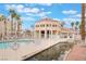 Community pool area with a uniquely designed clubhouse, surrounded by lush palm trees and a tranquil pond at 5000 Red Rock St # 120, Las Vegas, NV 89118