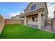 This backyard features green artificial turf, a covered patio, a brick walkway, and a tall privacy wall at 5040 Serene Skies St, Las Vegas, NV 89130