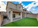Cozy backyard featuring green artificial turf, a covered patio with brick flooring, and a privacy wall at 5040 Serene Skies St, Las Vegas, NV 89130