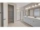 Bathroom featuring dual sink vanity, framed shower, a walk-in closet, and wood look tile floors at 5040 Serene Skies St, Las Vegas, NV 89130