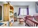 Neutral bedroom featuring a crib, a window with purple curtains, and a bookshelf at 5706 W Lake Mead Blvd, Las Vegas, NV 89108