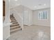 Inviting living room featuring neutral walls, tiled flooring, a staircase, and natural light from a large window at 6110 Scarlet Leaf St, Las Vegas, NV 89148