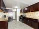 View of the kitchen with dark wood cabinetry, stainless steel appliances, and neutral tile backsplash at 6117 Borden Cir, Las Vegas, NV 89107
