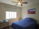 Bedroom with a ceiling fan, window, and a bed with blue comforter, complemented by an artwork at 75 N Valle Verde Dr # 1822, Henderson, NV 89074