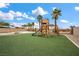Grassy backyard showcases a play set, bordered by palm trees and a privacy fence at 7825 Alameda Creek St, Las Vegas, NV 89113