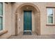 A close-up of a blue-green front door with an arched stone entryway and a brick walkway at 7825 Alameda Creek St, Las Vegas, NV 89113