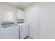 Bright laundry room with white washer and dryer and overhead cabinet at 92 Sea Holly Way, Henderson, NV 89074